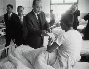 《省建設廳長慰問台北縣傷病礦工》截圖（1971），後方亦有隨行拍攝人員進行靜態攝影。