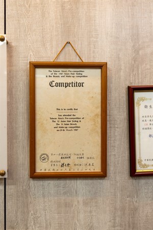 1987年老闆參加亞洲髮型、化妝大賽獲獎的獎狀，被掛在店內牆上展示。